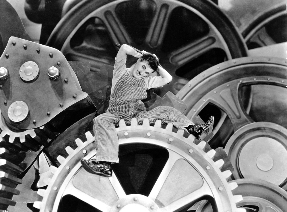 Charlie Chaplin sitting on top of a large gear