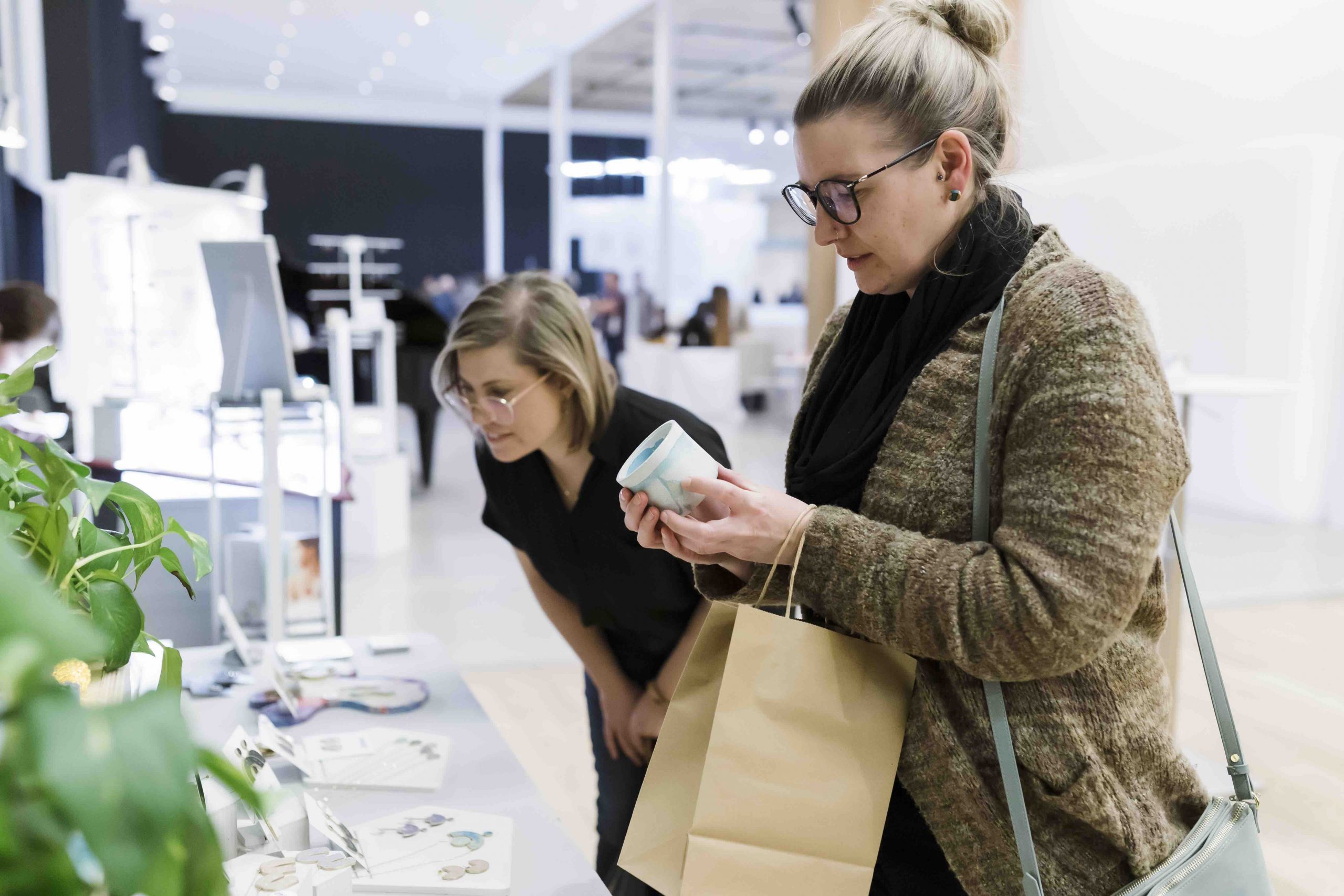 Two people look at items for sale at a Remai Modern shopping event.