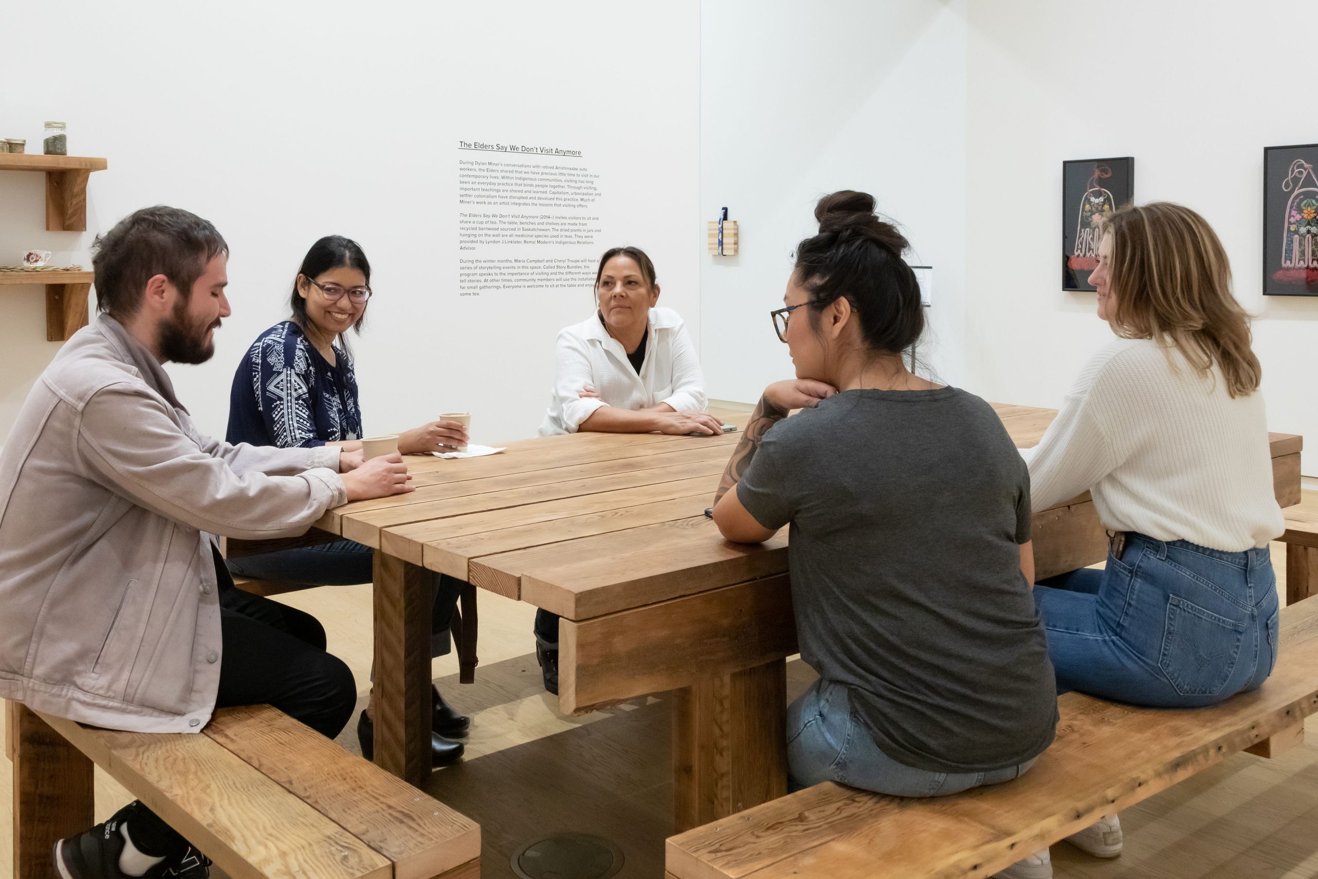 People gather around a table in exhibition Storied Objects: Métis Art in Relation.