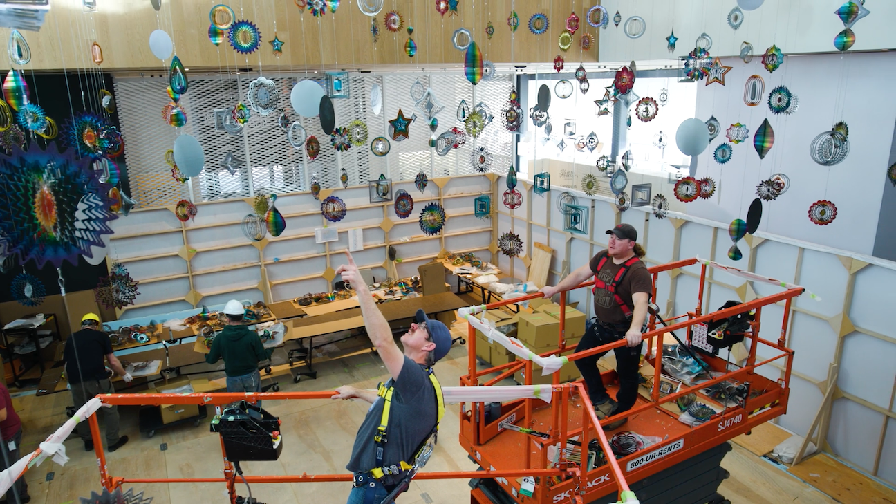 Two members of Remai Modern's preparatory team work on lifts as they install Nick Cave's Spinner Forest.
