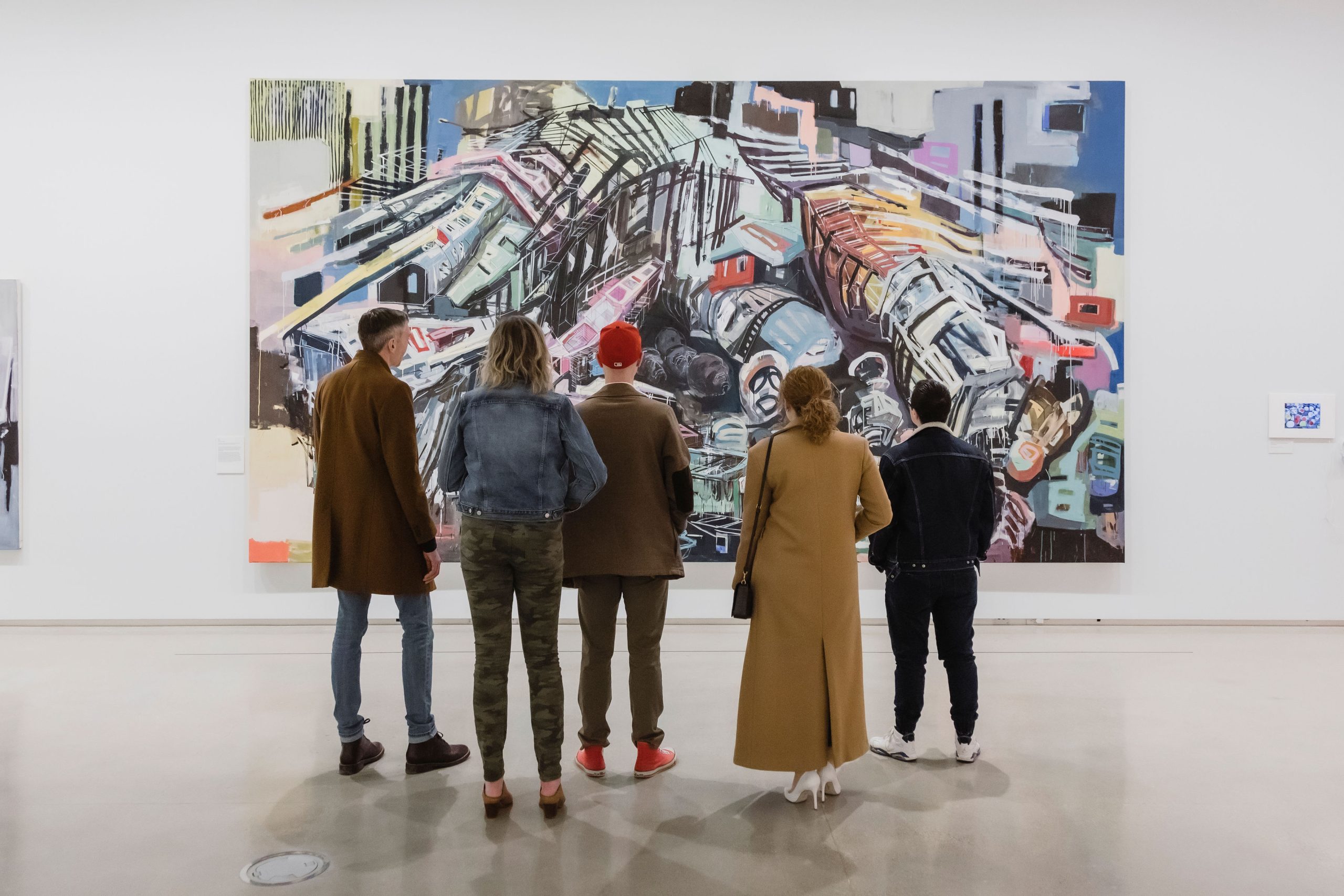 A group of people stand in front of a large abstract painting by Denyse Thomasos