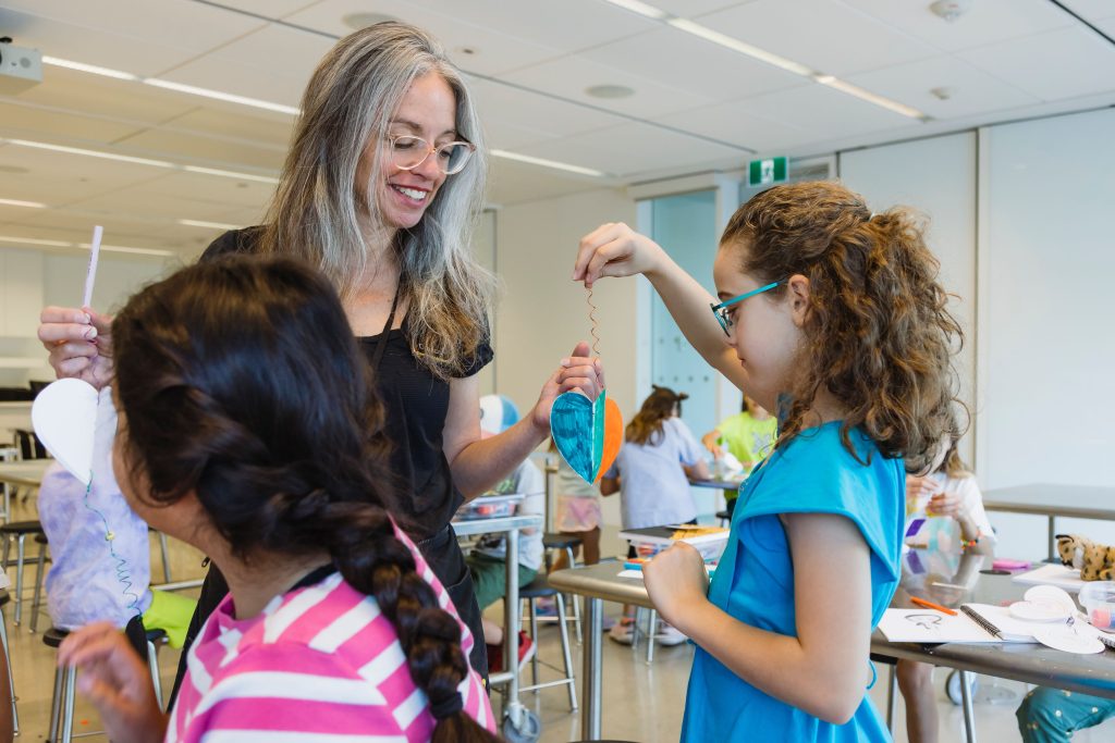 A Program Guide helps a child with their art mobile at one of Remai Modern's summer camps.