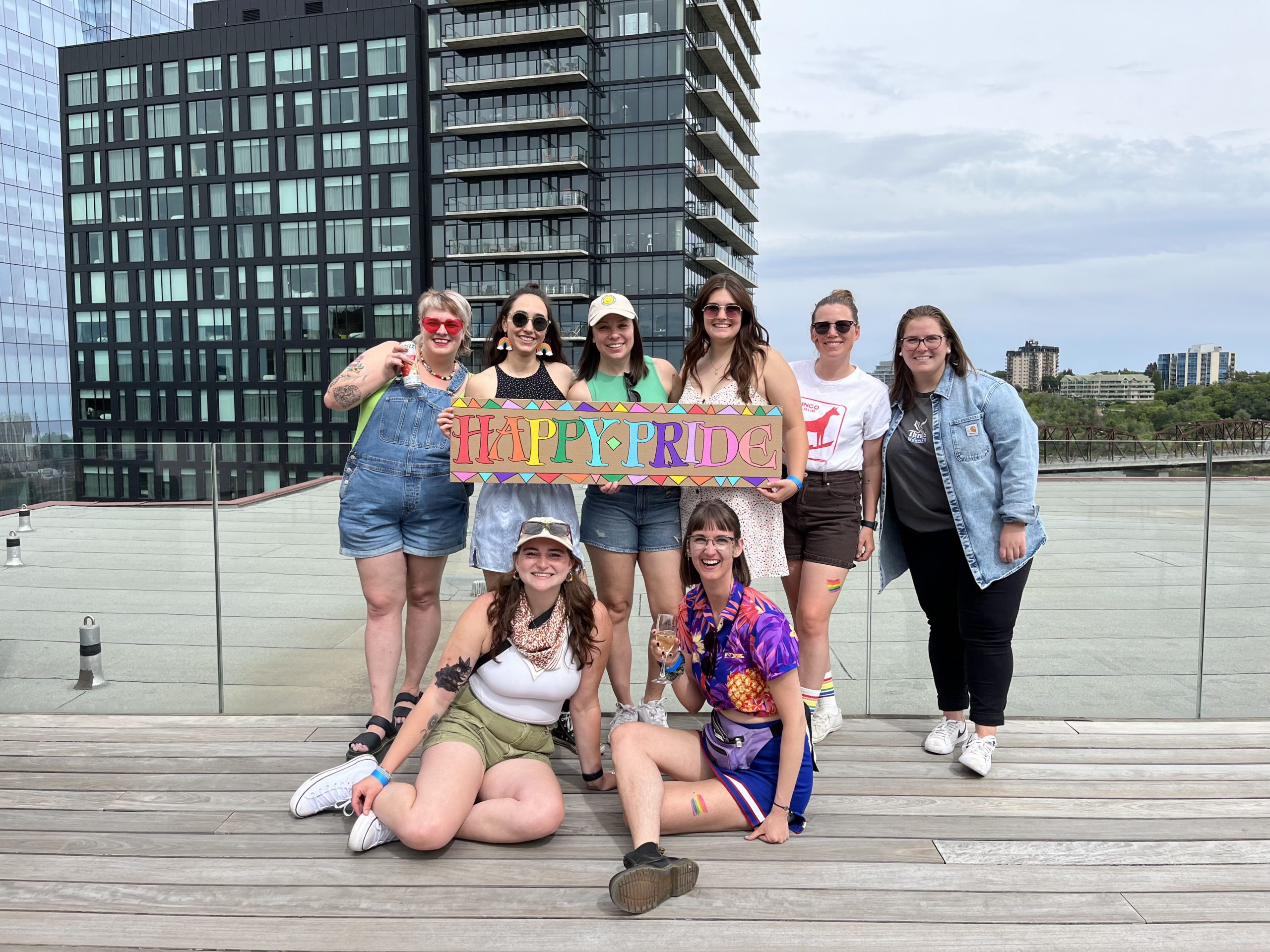 People hold a sign that says "Happy Pride" on Remai Modern's rooftop deck.