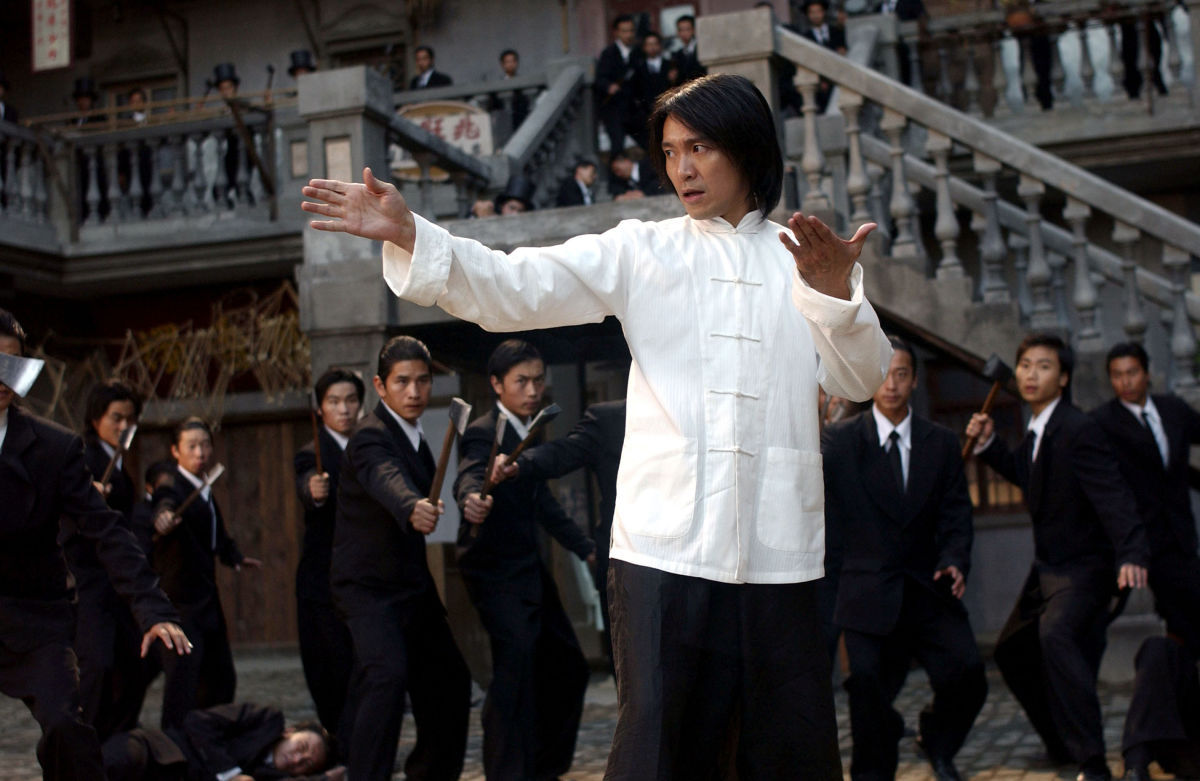 A Martial Artist poses while surrounded by a group of men in suits holding axes