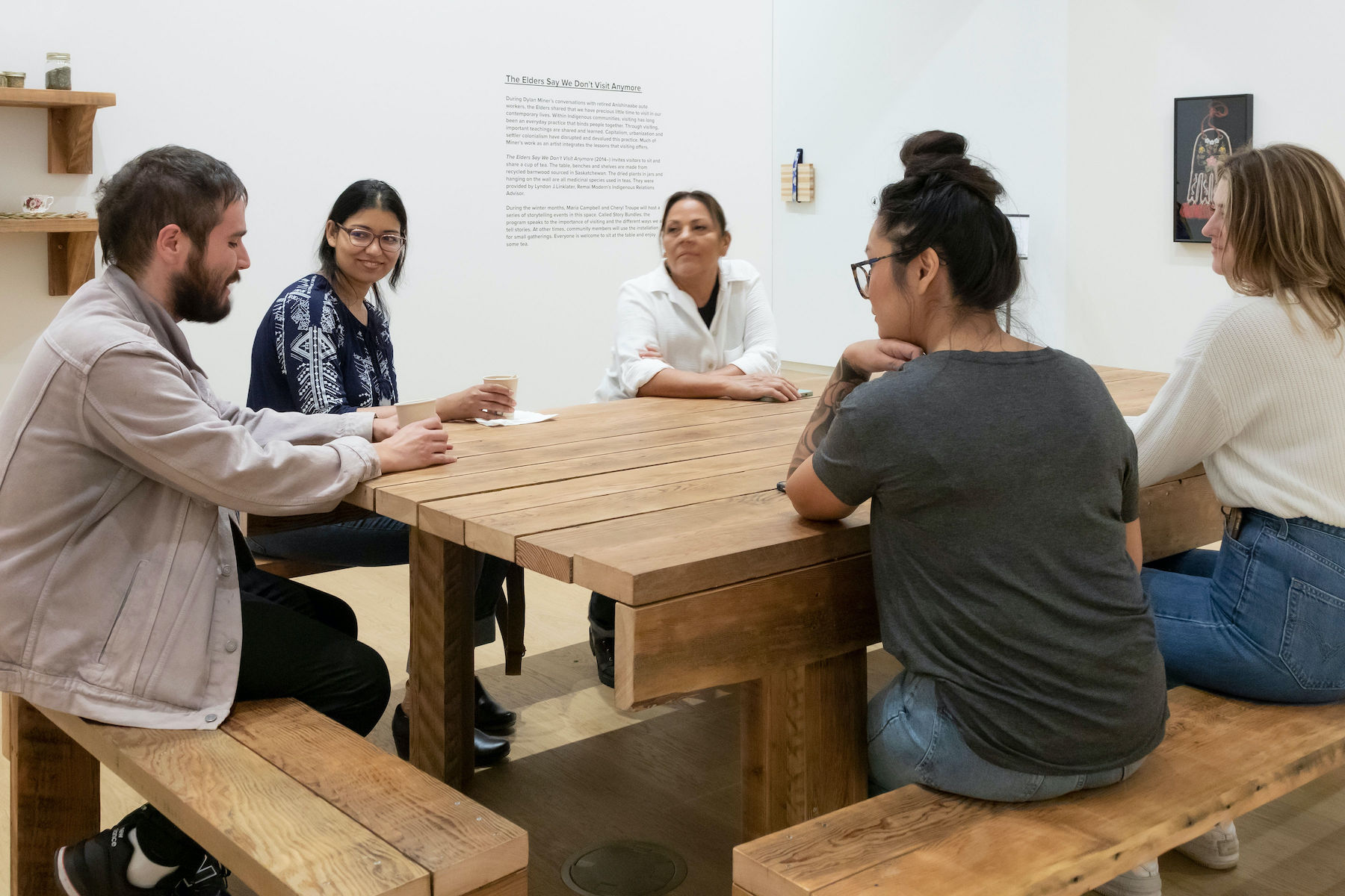 People gather around a table in exhibition Storied Objects: Métis Art in Relation.