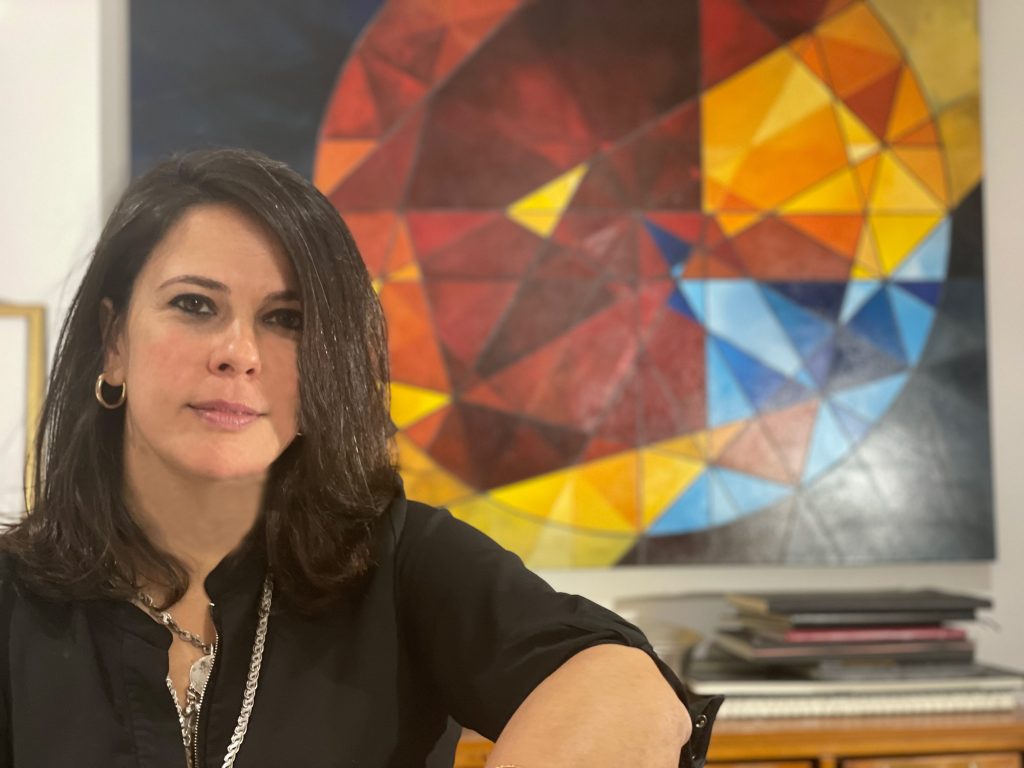 Artist Muveddet Al-Katib sits in front of one of her paintings.