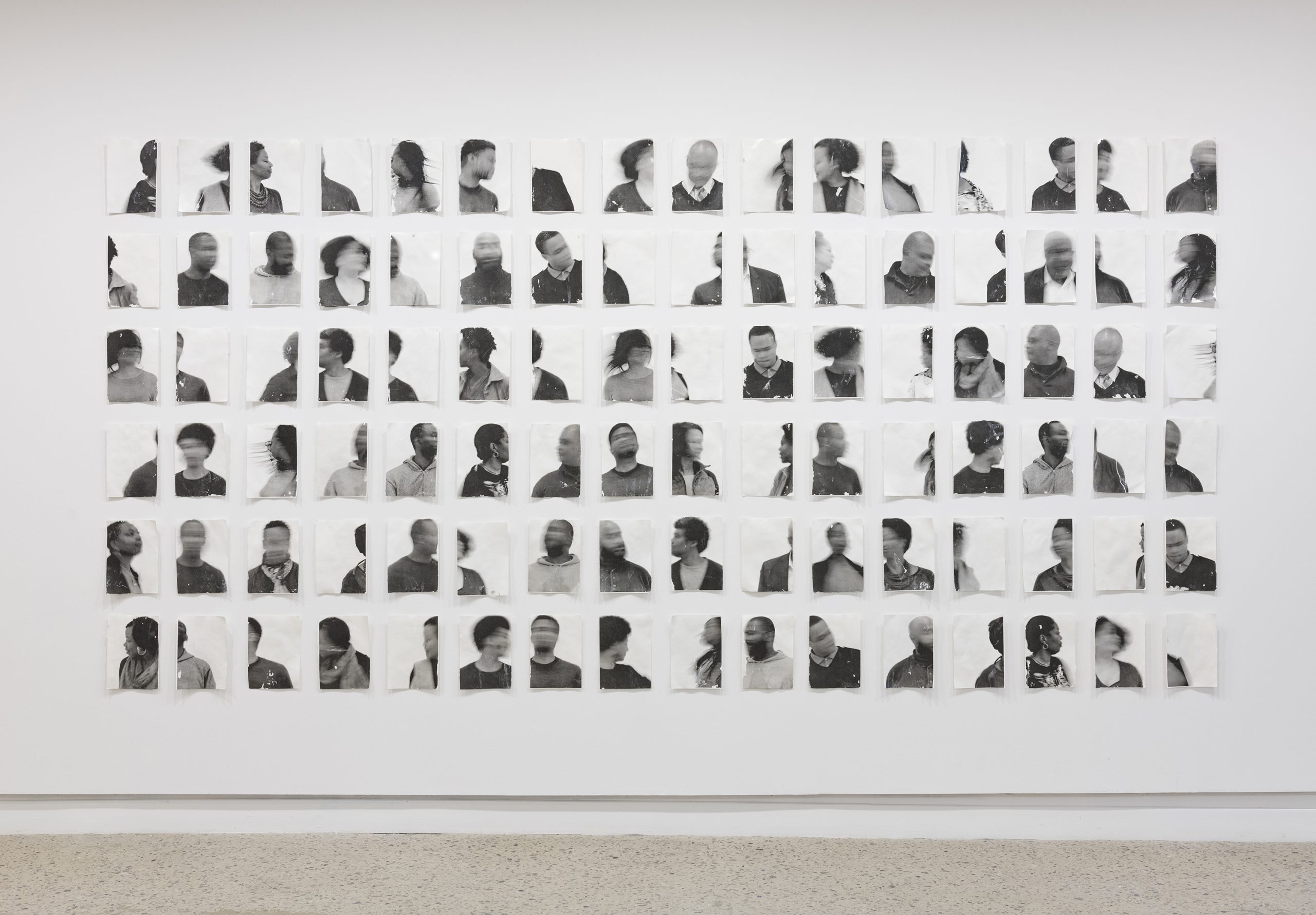 A grid of black and white photographs are hung on a wall. Each photograph depicts a person in blurred motion.