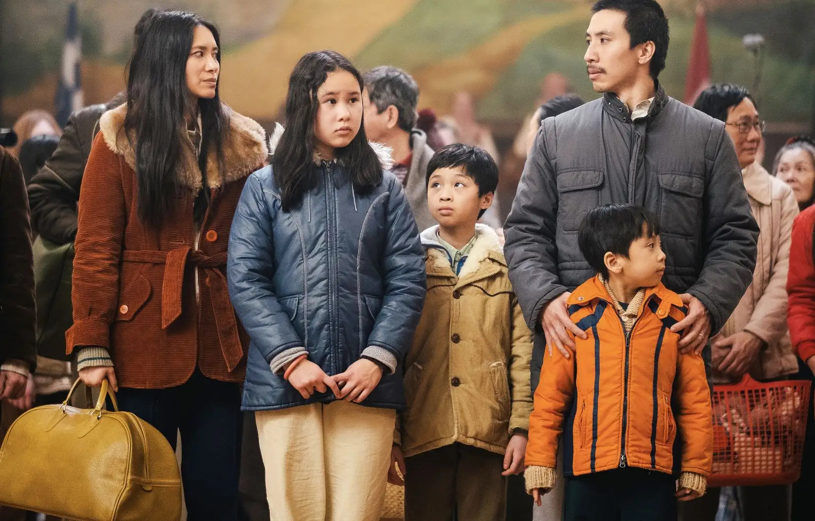 A family of children and adults stand together wearing winter jackets