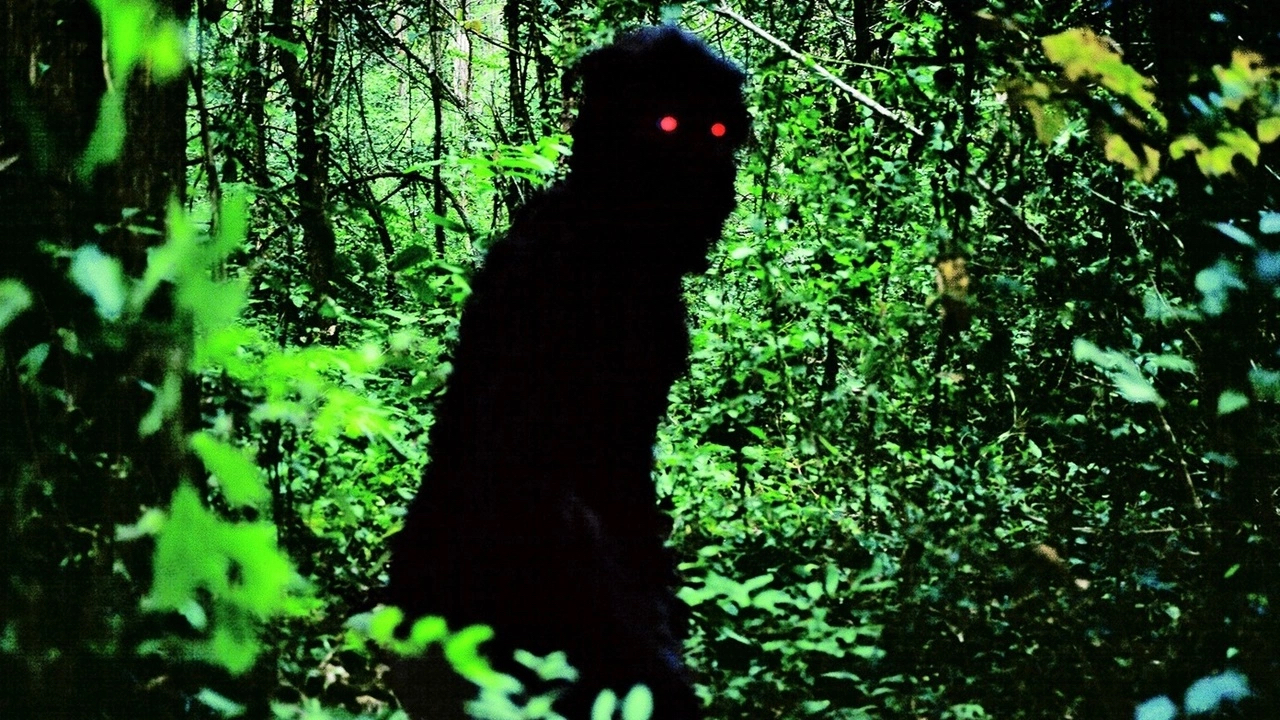A shadowed black figure with red eyes walks through a jungle scene