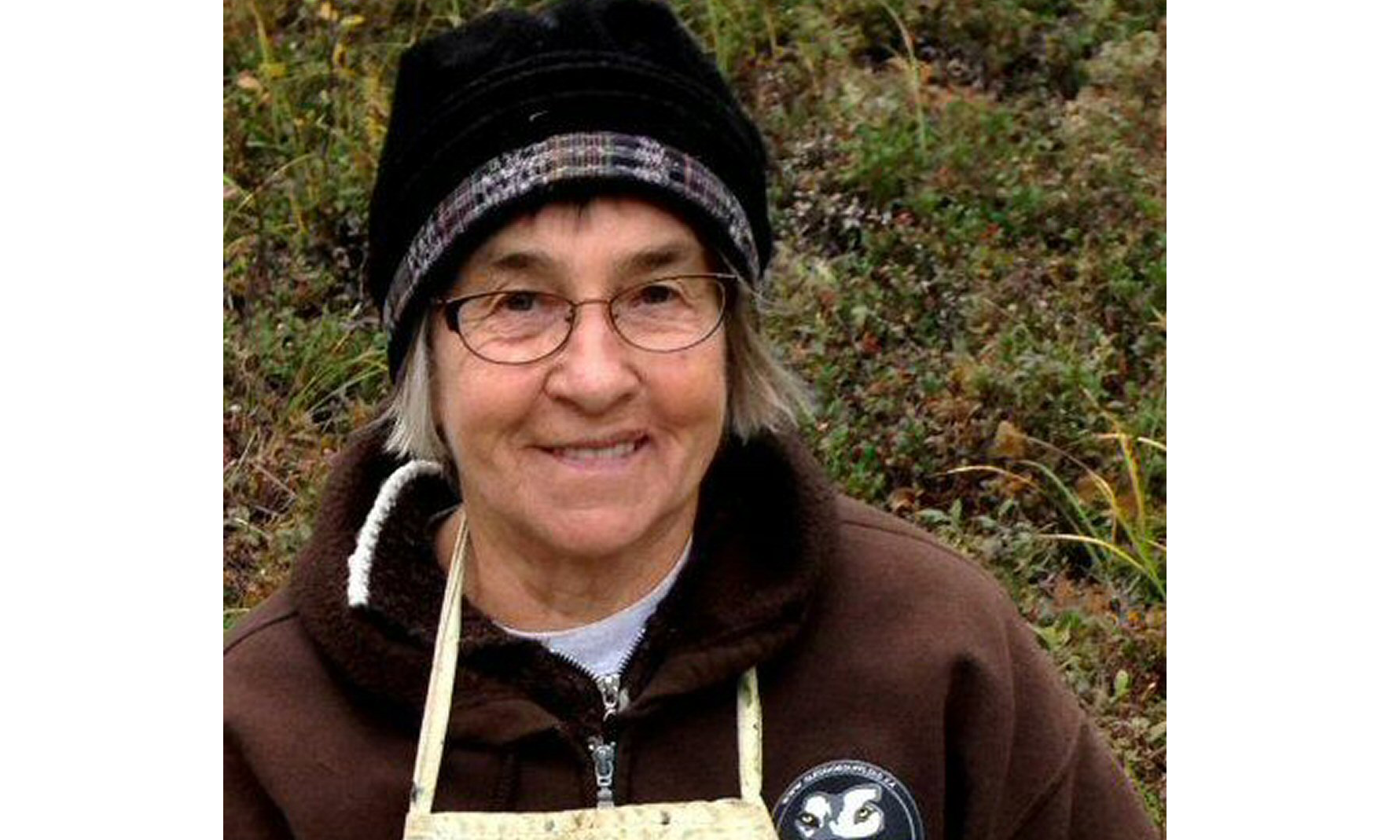 A photo of artist Rigmor Clark outside wearing a woolhat and a canvas apron
